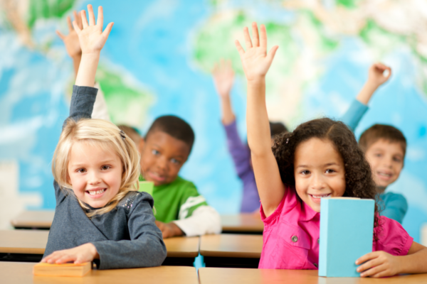 young students holding up hands in air